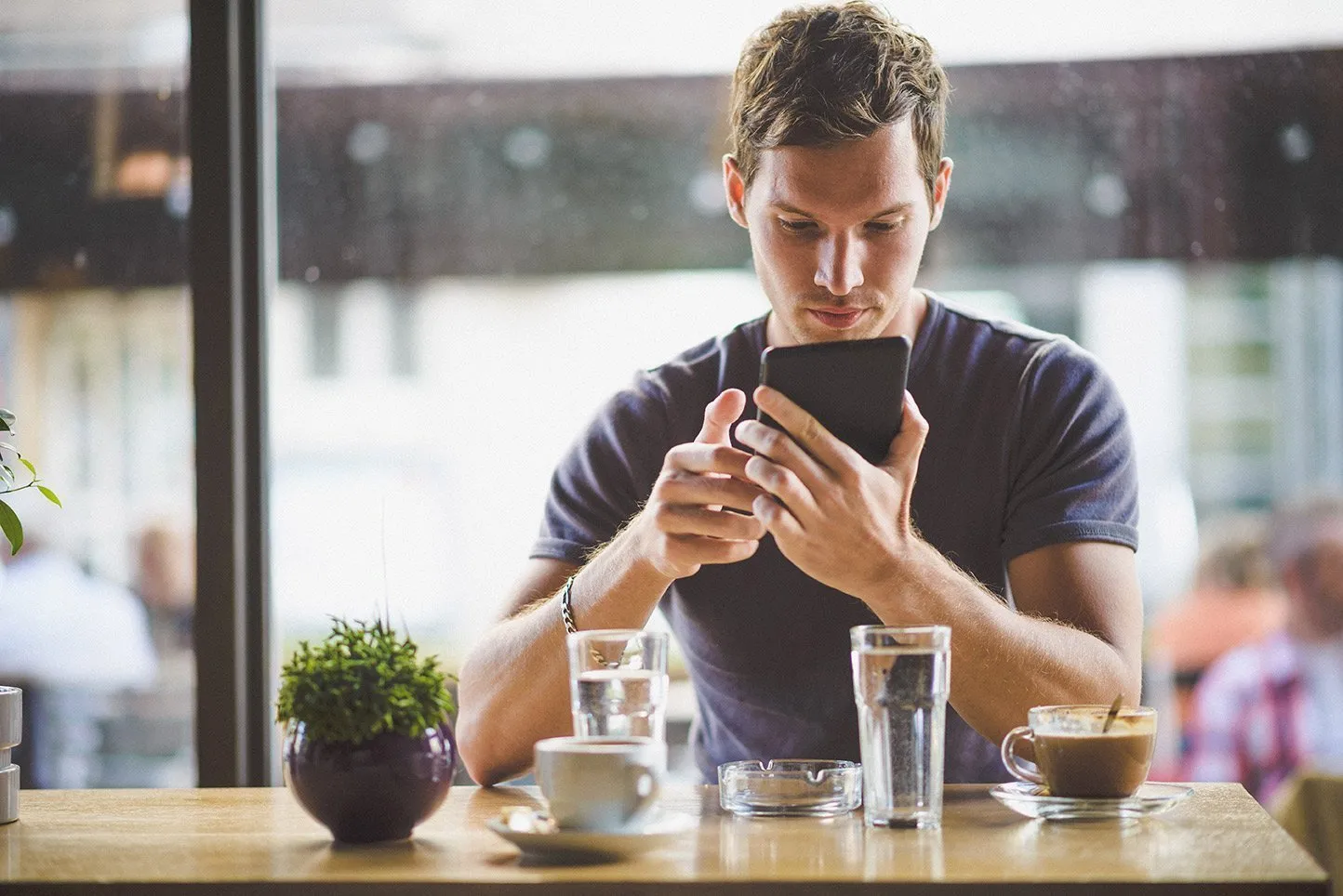 Man with mobile with glass of water on table